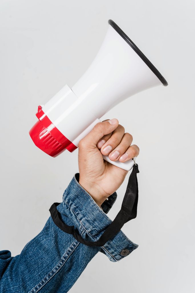 pexels photo 5935743 5935743 A person in a denim jacket holds a red and white megaphone, emphasizing communication.